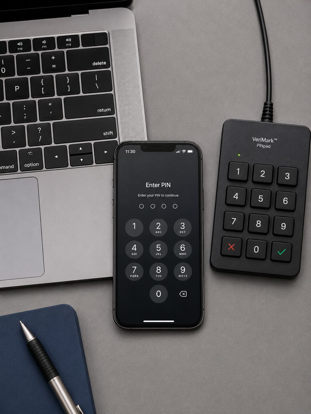 A photorealistic flat-lay photograph of a laptop keyboard, a smartphone showing a PIN entry screen, and a physical numeric PIN pad, arranged together on a plain desk surface. Soft, even studio lighting from above, neutral gray background, clean commercial product-photography style.